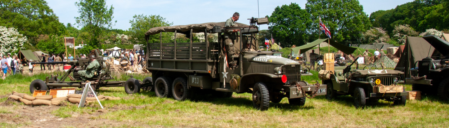 An army truck parked in grass alongside other vehicles, showcasing military presence and equipment.